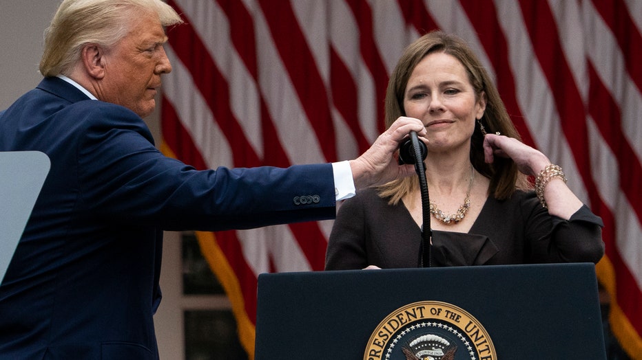 Trump touches a microphone on a lectern in front of Judge Amy Coney Barrett