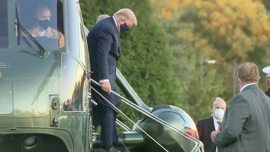 Trump, wearing a mask, walks down stairs from Marine One helicopter