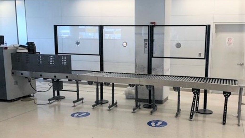 Acrylic barriers on one side of a baggage conveyor belt