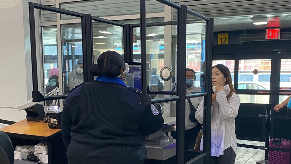 Clear acrylic barriers around a TSA officer's checkpoint