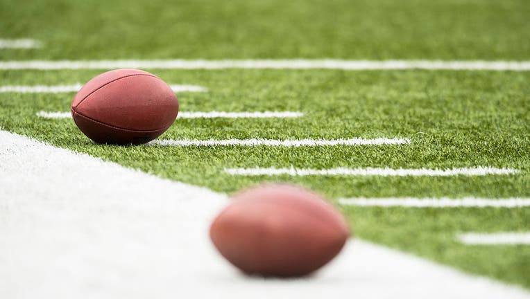 Footballs rest on the sideline before a game.