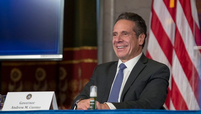 Cuomo smiles from behind a desk