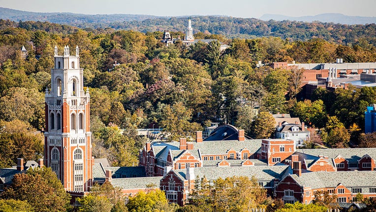 Aerial view of Yale University campus with many green trees, red brick tower and buildings and hills in the distance