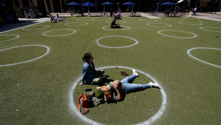 FILE - In this March 3, 2021, file photo, Kyree Kayoshi, his dog Kumi, and Miranda De Llano use circles marked for social distancing to help battle the COVID-19 virus as they relax at the Pearl Brewery in San Antonio.