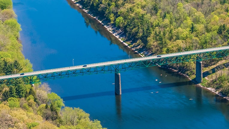Motor vehicle bridge over Delaware River connecting two green, wooded areas
