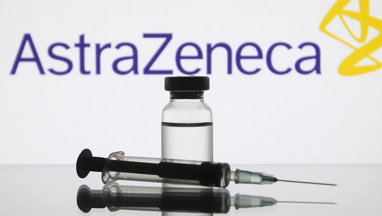 A medical syringe and a vial in front of the AstraZeneca British biopharmaceutical company logo.(Photo by STR/NurPhoto via Getty Images)