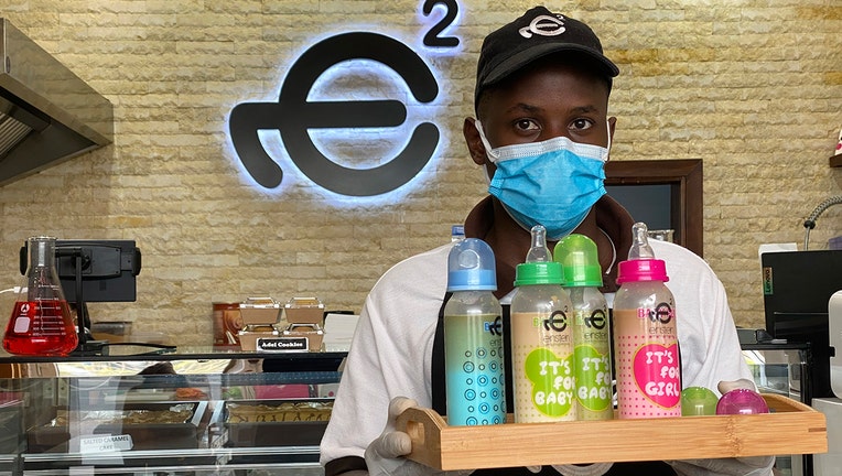 A waiter poses with a tray of baby bottles that he brought out from storage, at Einstein Cafe in Dubai, United Arab Emirates, Sunday, March 14, 2021. (AP Photo/Kamran Jebreili)