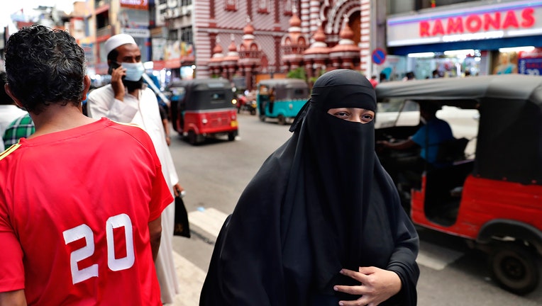 A burqa clad Sri Lankan Muslim woman walks in a street of Colombo, Sri Lanka, Saturday, March 13, 2021. Sri Lanka on Saturday announced plans to ban the wearing of burqas and said it would close more than 1,000 Islamic schools known as madrassas, citing national security. (AP Photo/Eranga Jayawardena)