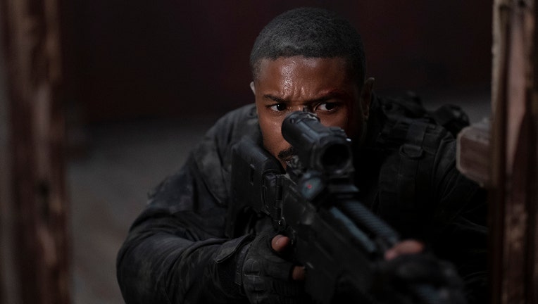 Actor Michael B. Jordan looks into a scope while he aims a rifle