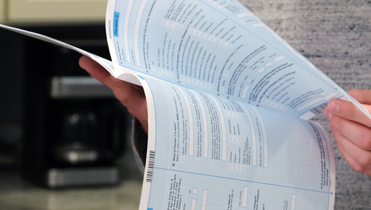 Close up image of a person's hands holding a Census long form booklet