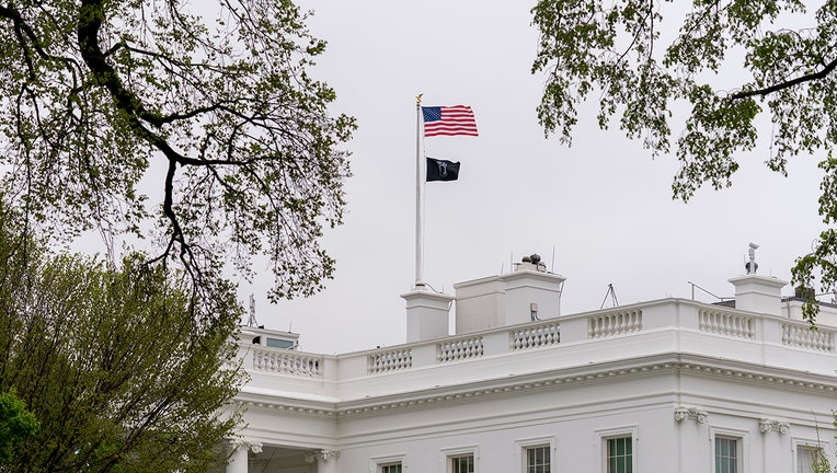 A POW/MIA flag, symbolizing America's Missing in Action and Prisoners of War, flies along with the American flag above the White House, Friday, April 9, 2021, in Washington. (AP Photo/Andrew Harnik)