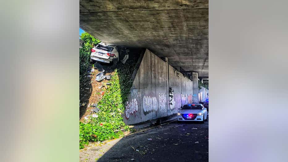 This photo provided by the California Highway Patrol shows the scene where a man fleeing from the CHP totaled his girlfriend's Maserati SUV after he careened up an embankment and slammed into the underside of an overpass, wedging the car under a freeway in Oakland, Calif., on Monday, April 12, 2021. (California Highway Patrol