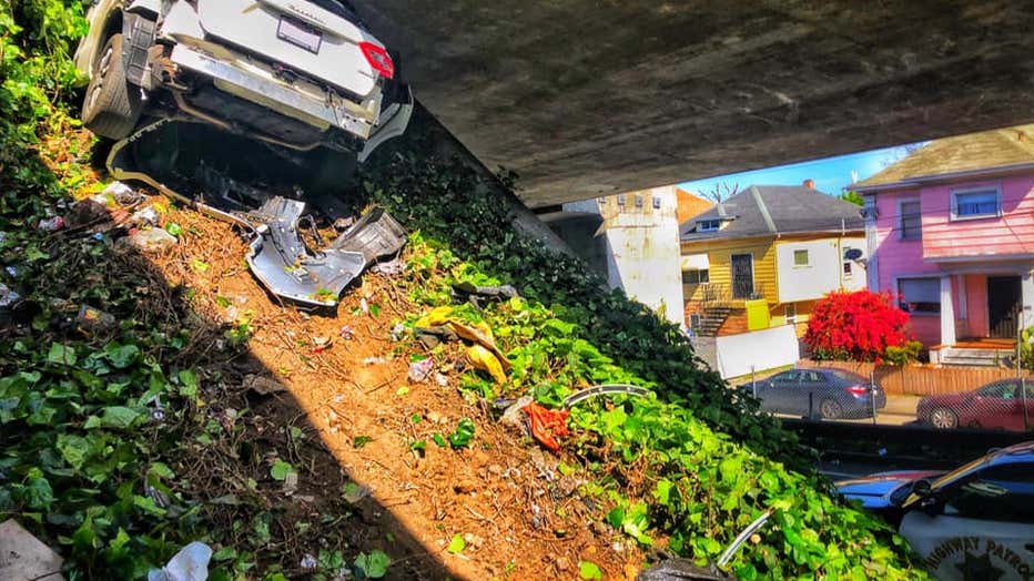 This photo provided by the California Highway Patrol shows the scene where a man fleeing from the CHP totaled his girlfriend's Maserati SUV after he careened up an embankment and slammed into the underside of an overpass, wedging the car under a freeway in Oakland, Calif., on Monday, April 12, 2021. (California Highway Patrol