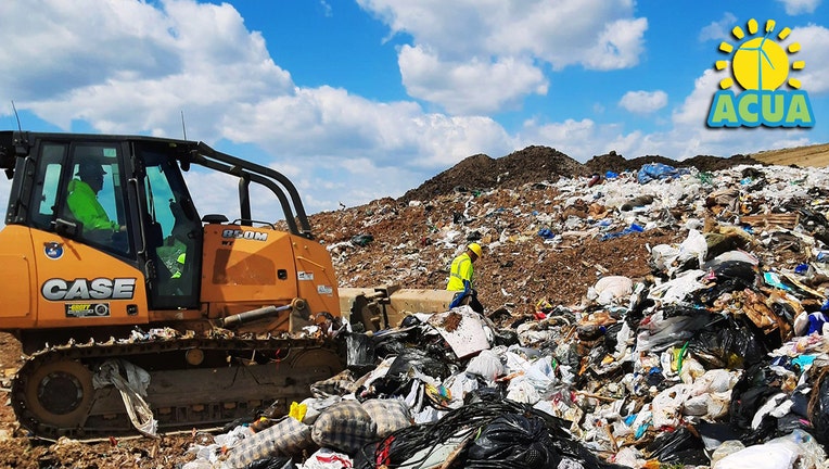 Heavy equipment and workers search a huge pile of trash at a landfill