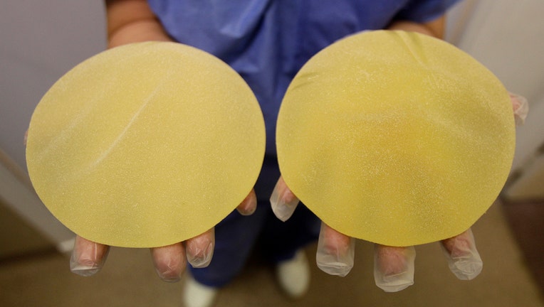 A closeup view of a nurse's hands holding a pair of yellow breast implants