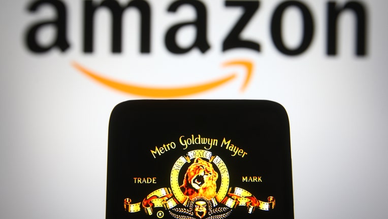 The MGM logo is seen on a smartphone screen with an Amazon logo in the background.