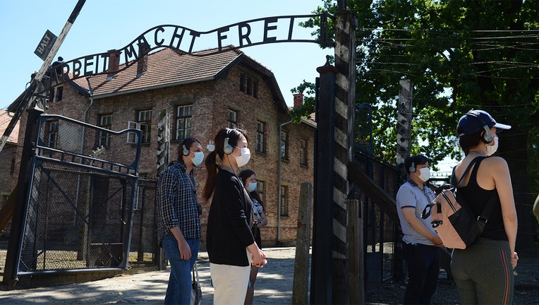 Visitors are seen near the gate with its inscription "Work sets you free" as the memorial site of the former German Nazi death camp Auschwitz in Oswiecim.(Photo by BARTOSZ SIEDLIK/AFP via Getty Images)
