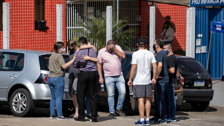 Relatives gather outside the Aquarela preschool in Saudades, in the southern state of Santa Catarina, Brazil, Tuesday, May 4, 2021. According to police an 18-year-old teenager entered the day care center with a knife and stabbed and killed three children and a teacher. (AP Photo/Liamara Polli)