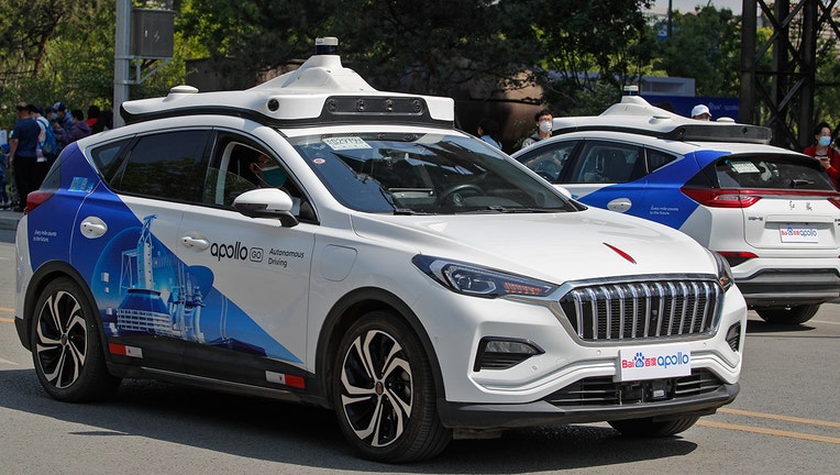 Baidu Apollo Robotaxis move on a street at the Shougang Park in Beijing, Sunday, May 2, 2021. Chinese tech giant Baidu rolled out its paid driverless taxi service on Sunday, making it the first company that commercialized autonomous driving operations in China. (AP Photo/Andy Wong)