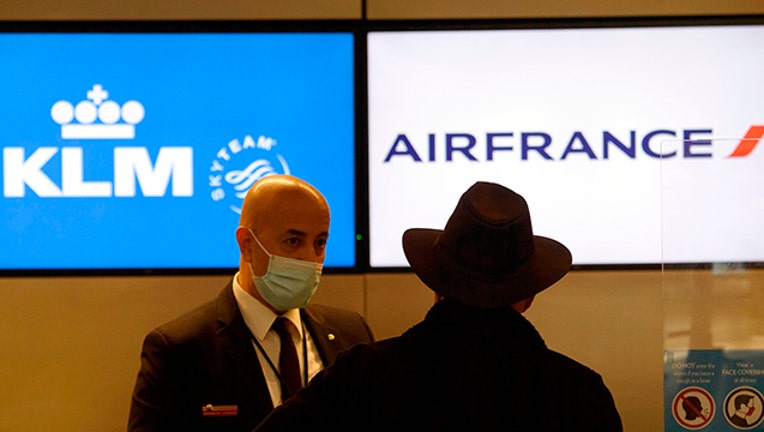 An employee wears a face mask as a passenger checks-in for a flight at a Air France and KLM counter.(File Photo by PATRICK T. FALLON/AFP via Getty Images)