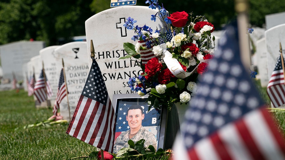 Flowers, flags and a framed photo decorate a soldier's headstone at Arlington National Cemetery