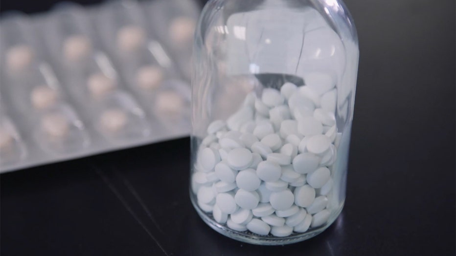 A clear bottle containing white pills; a blister pack containing pills