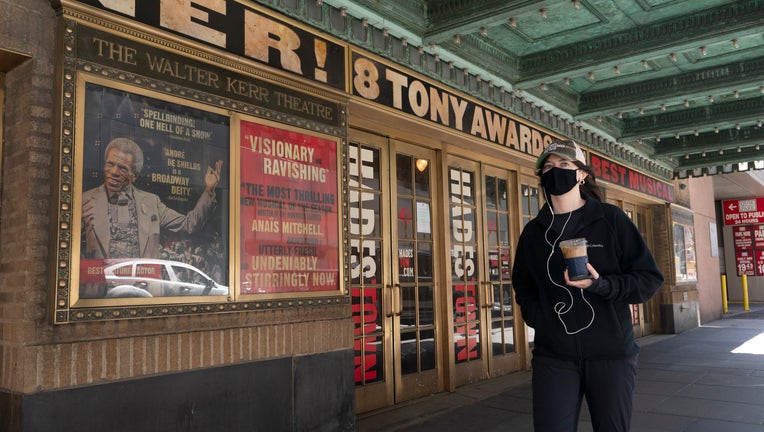 A woman walks past the Walter Kerr Theatre, Thursday, May 6, 2021, in New York where Hadestown was showing before the coronavirus pandemic forced its closing a year ago.