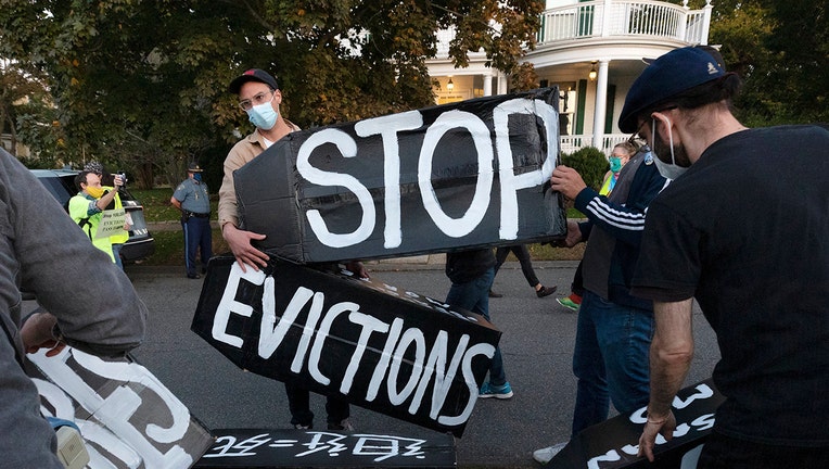 Activists wearing masks and holdings signs that say 'stop evictions'