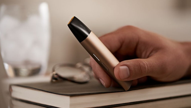 A closeup of a hand holding an electronic cigarette