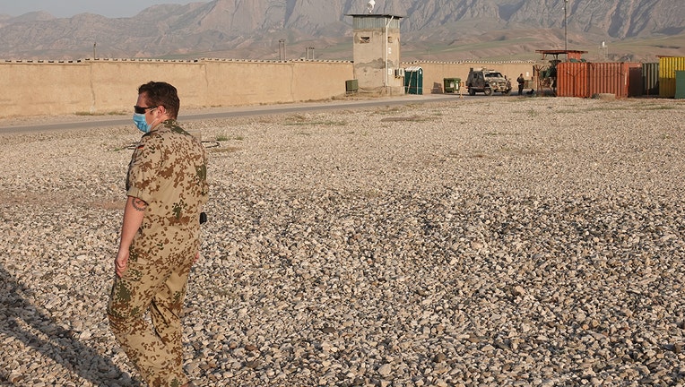 A soldier stands in front of an outer wall of Camp Marmal with a watchtower. (Photo by Michael Fischer/picture alliance via Getty Images)