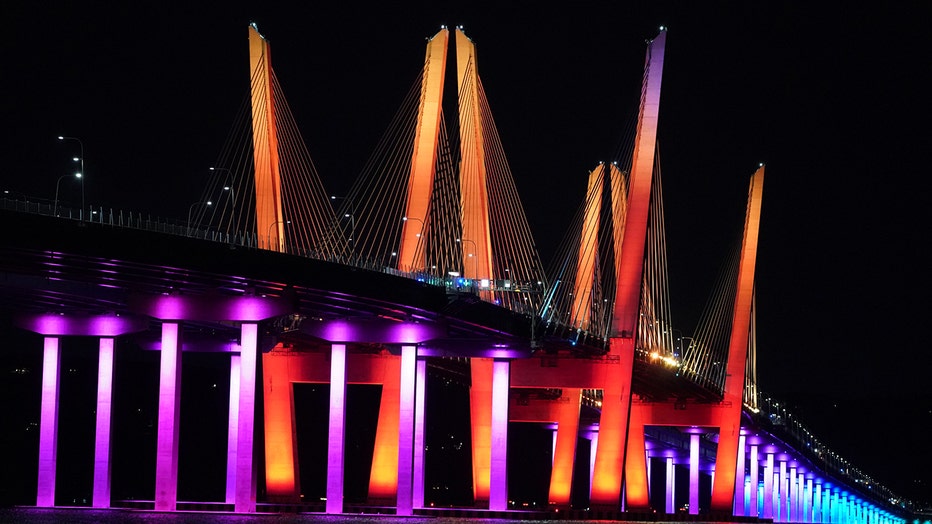 A bridge over the Hudson lit red, orange, yellow, green, blue and violet