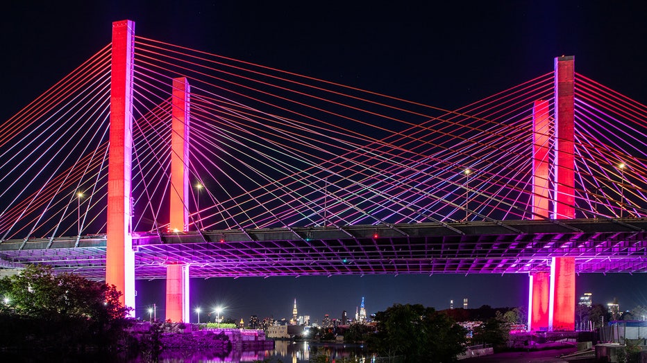 A New York City bridge lit red, orange, yellow, green, blue and violet