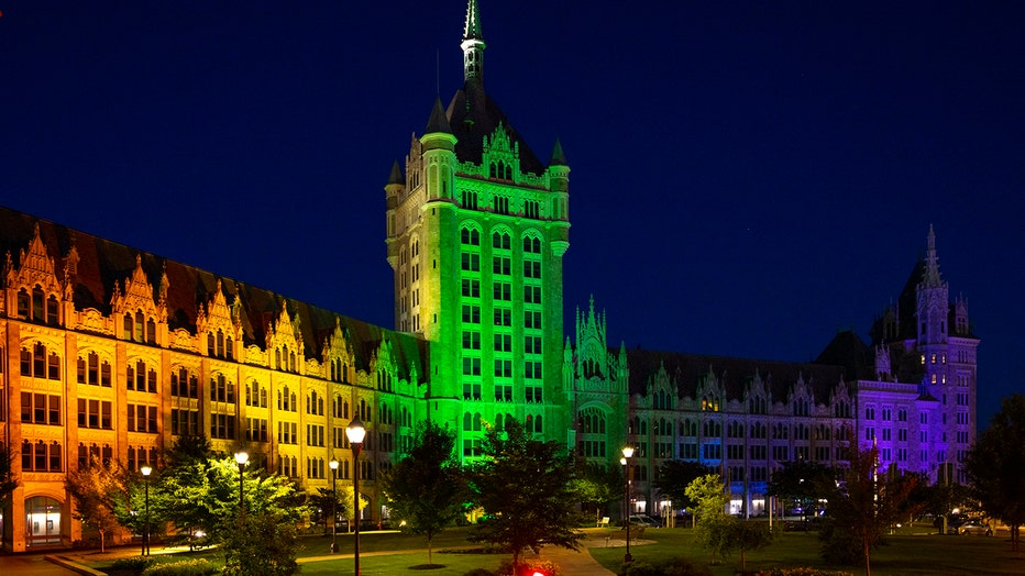 A SUNY building lit red, orange, yellow, green, blue and violet