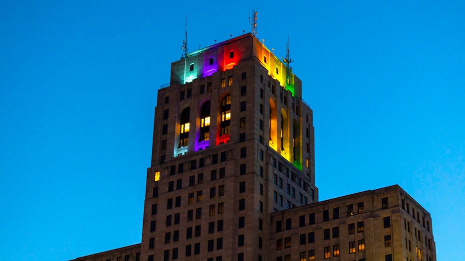 Pride colors illuminate the top of a state office building in Albany
