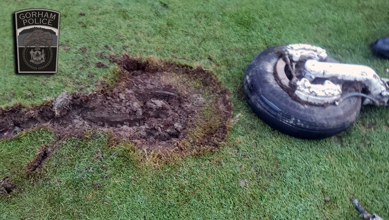 A wheel and strut and the crater it caused in a golf course