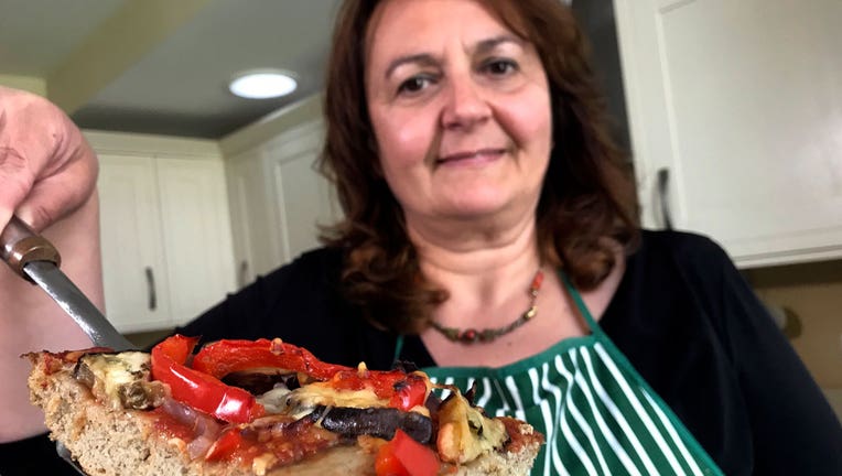 Tiziana di Costanzo, co-founder of Horizon Insects, holds up a slice of pizza made with cricket powder, in her London kitchen on June 2, 2021. (AP Photo/Kelvin Chan)