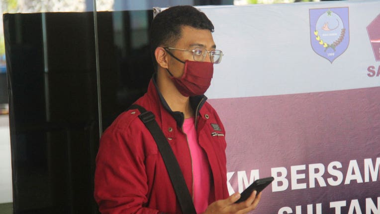 In this July 18, 2021, photo, a man who used a fake identity arrives at the Sultan Babullah airport in Ternate, Indonesia. The man with the coronavirus boarded a domestic flight disguised as his wife, wearing a niqab covering his face and carrying fake IDs and a negative PCR test result. He was arrested upon landing and tested positive for COVID-19. (AP Photo/Harmoko)