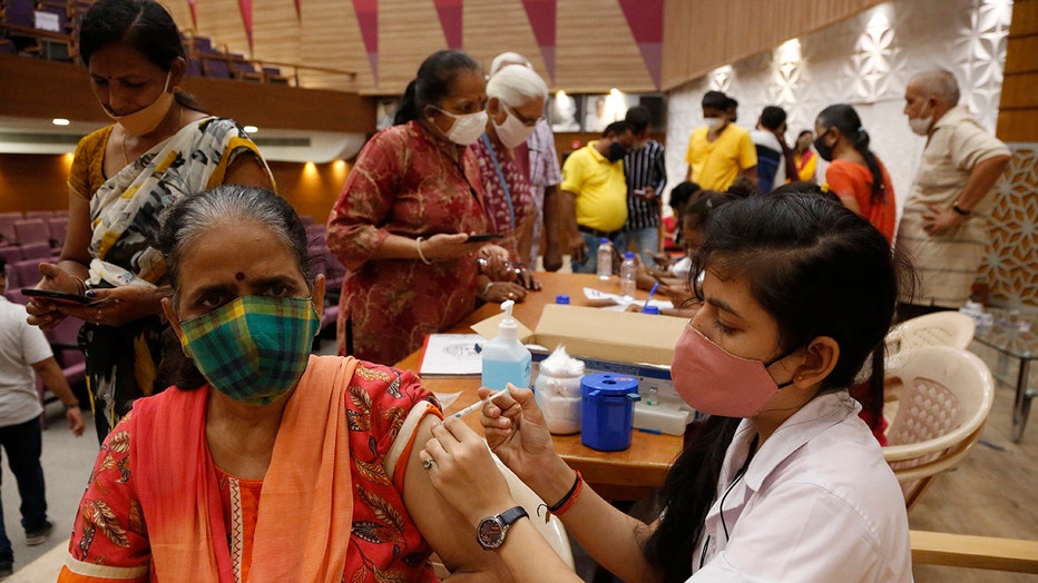 A health worker gives a vaccine shot to a woman