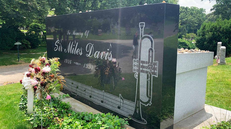 Closeup of a black headstone etched with the words "In Memory Of Sir Miles Davis 1926-1991"