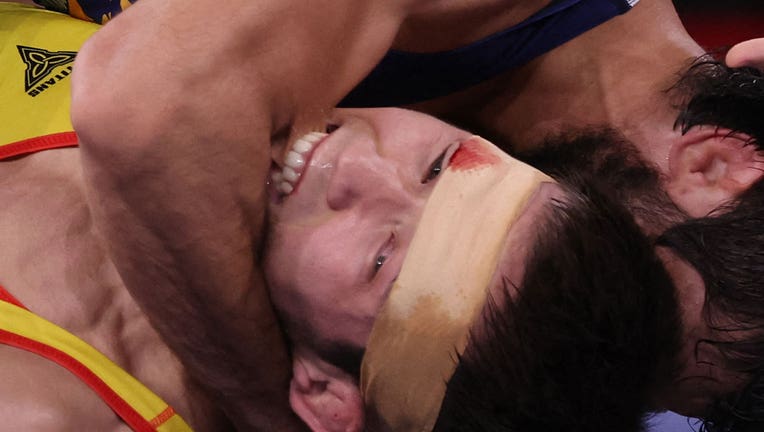 Kazakhstan's Nurislam Sanayev bites India's Kumar Ravi as he wrestles him in their men's freestyle 57kg wrestling semi-final match during the Tokyo 2020 Olympic Games on August 4, 2021. (Photo by JACK GUEZ/AFP via Getty Images)