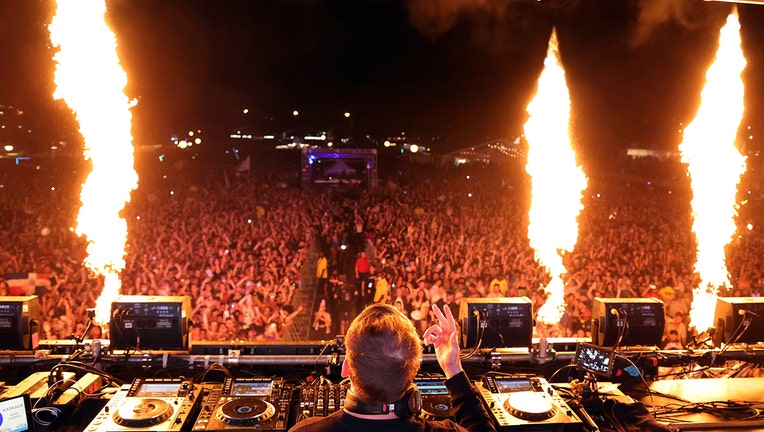 Kaskade performing on stage in front of thousands of fans; pyrotechnics alight