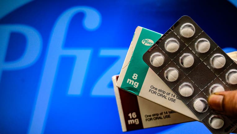 Medicine pills are seen with Pfizer logo
