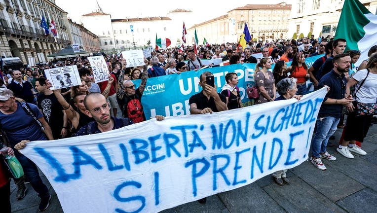 People hold a banner reading " Liberty dont ask, on take" as they demonstrate against the introduction of a mandatory sanitary pass called "green pass" in the aim to limit the spread of the Covid-19, at the Piazza Porta Palazzo in central Turin on September 11, 2021 (Photo by Tino Romano / ANSA / AFP)
