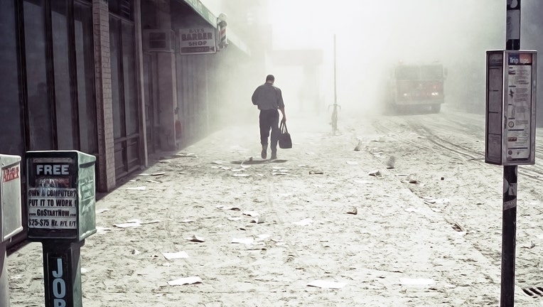 a man walks alone down the deserted sidewalk into the dusty mist; the streets are covered with debris, white dust and ashes from the disaster