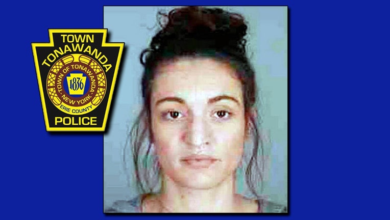 A booking photo of a woman with dark hair and a police department logo