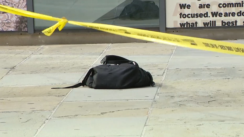 Yellow crime scene tape and a black backpack on the sidewalk
