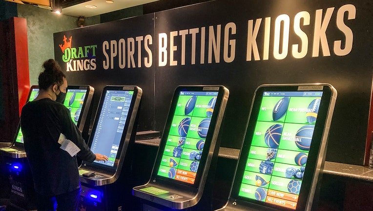A person wearing a mask uses a sports wagering kiosk