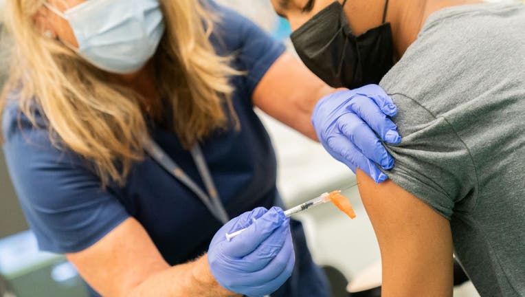 A healthcare worker administers a dose of the Pfizer-BioNTech Covid-19 vaccine to a student during a 'Vax To School' campaign event at a high school in the Staten Island