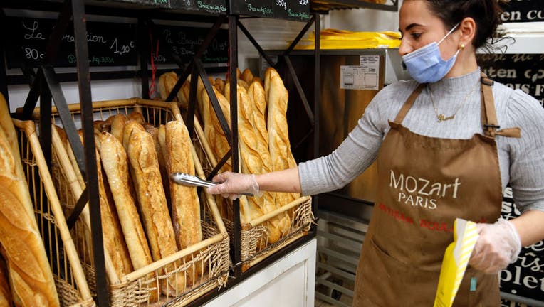 A baker holds a freshly baked baguette