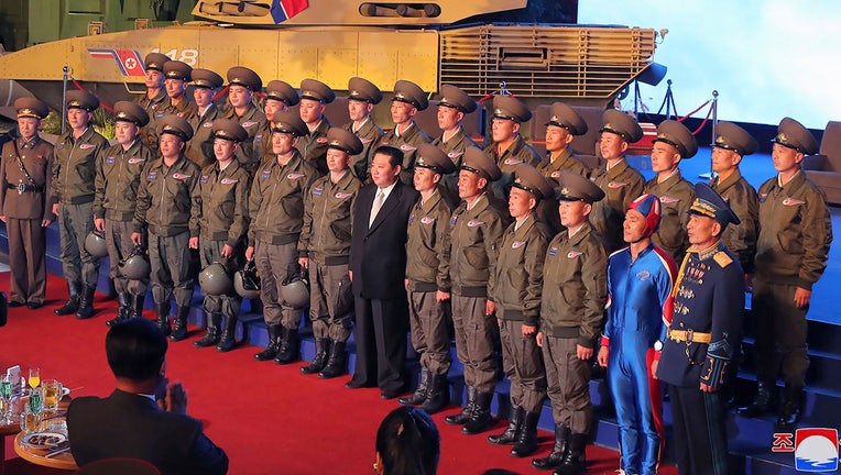 In this photo provided by the North Korean government, North Korean leader Kim Jong Un, center, poses for a group photo with fighter pilots who made the demonstration flight at the opening of an exhibition of weapons systems in Pyongyang, North Korea, Monday, Oct. 11, 2021.(Korean Central News Agency/Korea News Service via AP)